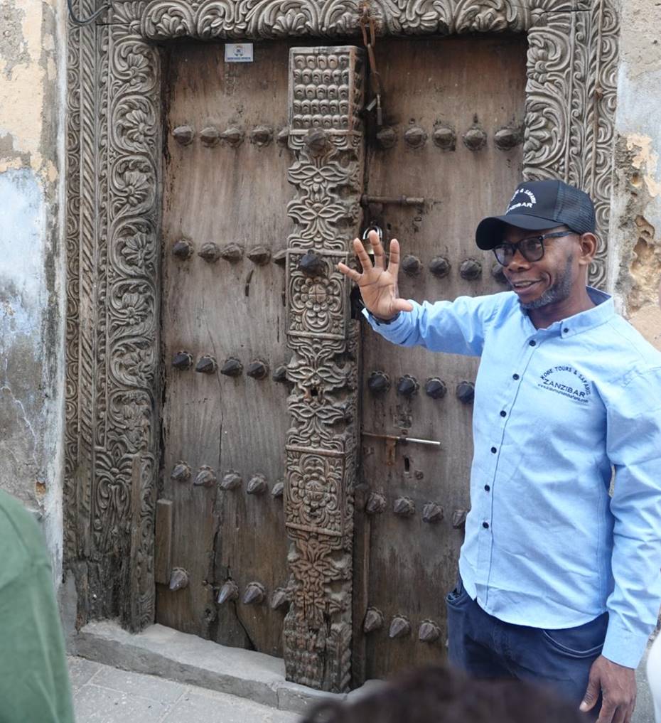 Khamis Kingo devant une porte sculptée de Stone Town